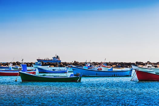Boats on the water in harbor or port with ship at background