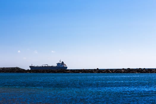 Cargo ship on the water. View from shore through breakwater