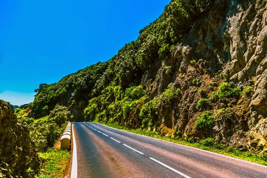 Asphalt road in green mountains with blue sky in Tenerife Canary island, Spain at spring or summer