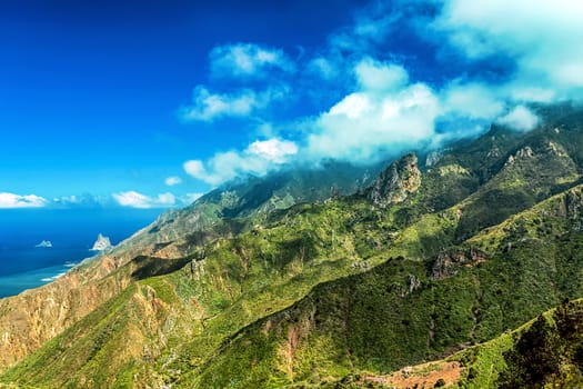 Clouds and green mountains or rocks with blue sky background near the Atlantic ocean landscape in Tenerife Canary island, Spain