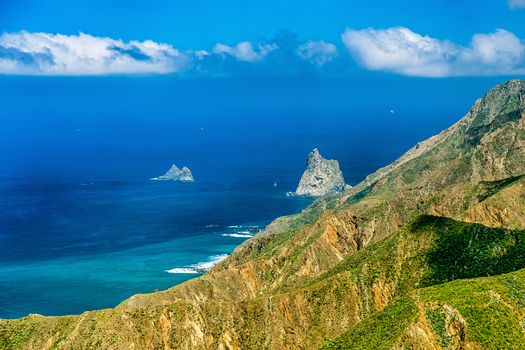 Coast or shore of Atlantic ocean with green mountain or rock and blue sky with skyline or horizon in Tenerife Canary island, Spain at spring or summer