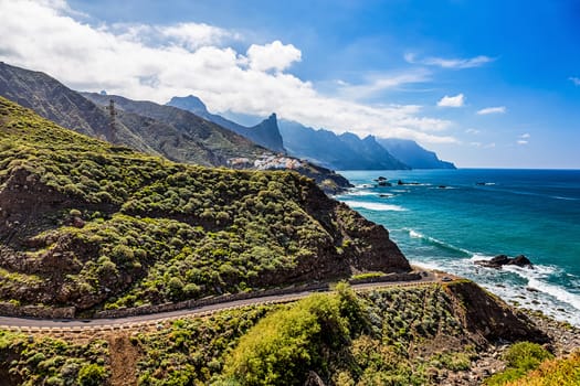 Road near coast or shore of Atlantic ocean with mountains and blue sky with clouds and skyline or horizon in Tenerife Canary island, Spain at spring or summer