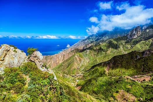 Green mountains or rocks with clouds over peak and blue sky horizon near the Atlantic ocean landscape in Tenerife Canary island, Spain