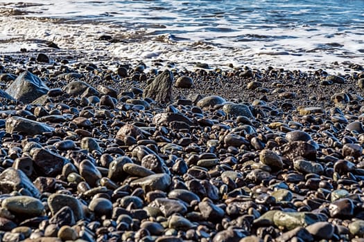 Stones and water with waves on the beach coast or shore of ocean or sea