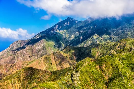 Green rocks with white clouds on blue sky landscape in Tenerife island, Spain