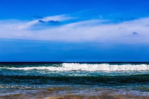 Atlantic ocean with waves and blue sky with clouds on background