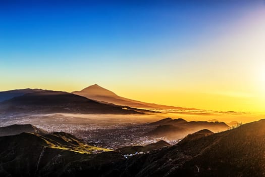 Sunset in mountains and blue sky with fog or haze and Teide volcano on background in Tenerife Canary island, Spain at spring or summer
