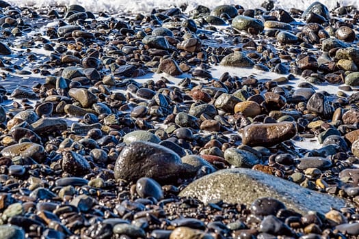 Stones with foam on the beach shore of ocean or sea