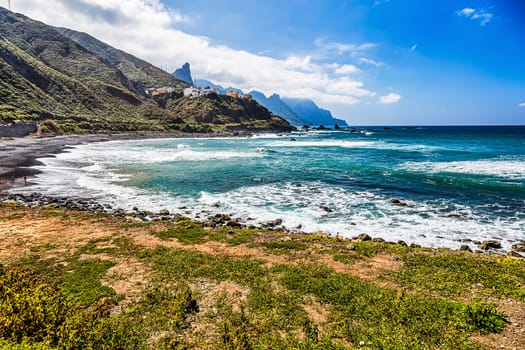 Coast or shore of Atlantic ocean with green mountain or rock and  sky with clouds and skyline or horizon in Tenerife Canary island, Spain at spring or summer