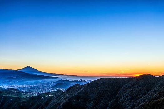 Sunset in mountains and blue sky with haze and Teide volcano on background in Tenerife Canary island, Spain at spring or summer
