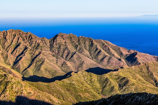 Coast of Atlantic ocean with green mountain or rock and blue sky with skyline or horizon in Tenerife Canary island, Spain at spring or summer
