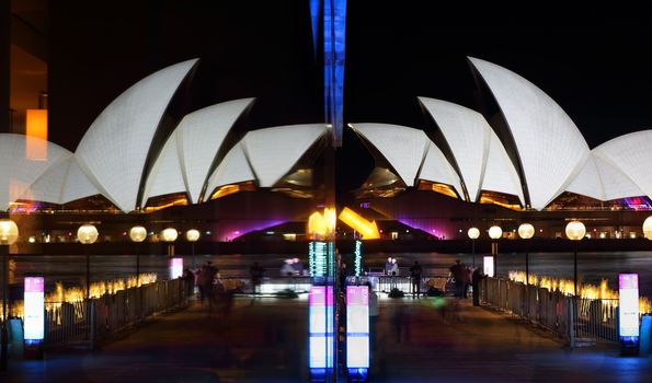 SYDNEY, AUSTRALIA - MAY 27, 2015; Sydney Opera House and glass reflections with Your Are Here light installation at the end of the pier.  Public and tourists have their photo taken under the sign using hashtag #howselfieswork.  Please note glass reflections are distorted