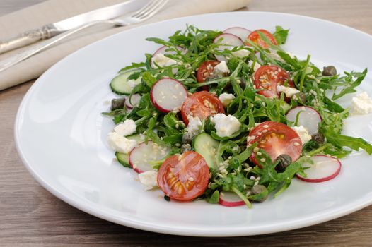 Vegetable salad with arugula, feta ,olive dressing and  sesame seeds