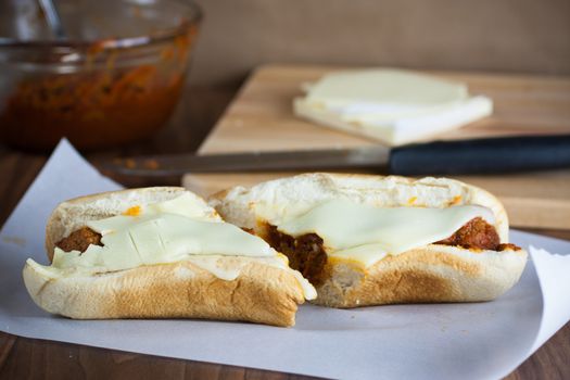 A fresh meatball sandwich with cheese on parchment paper.