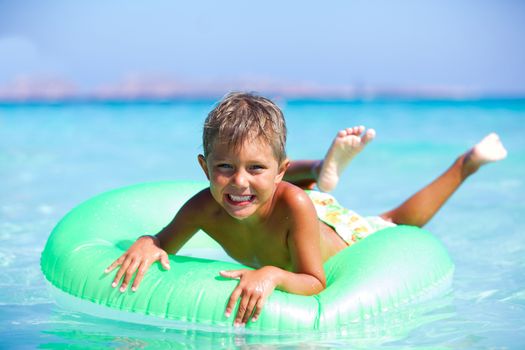 Happyboy playing on the inflatable rubber circle in the sea