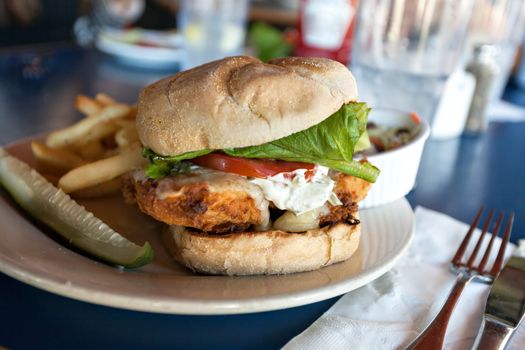 Fried fish sandwich with tartar sauce and french fries.