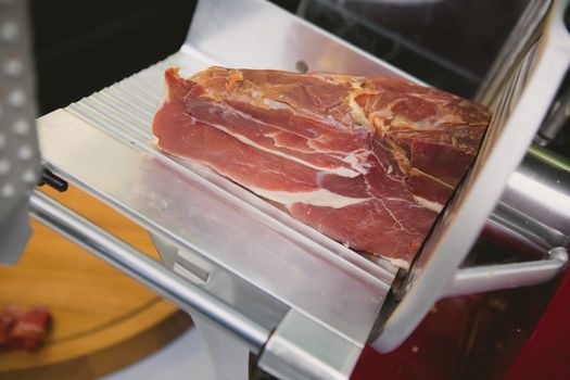 Waiter is slicing prosciutto in restaurant, toned image