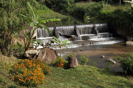 Small weir in valley with water flowing over