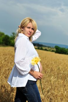pregnant woman standing in summer sunny wheat field