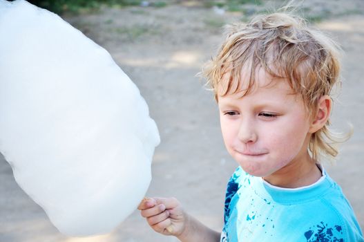 little boy holding cotton candy in hot summer day 