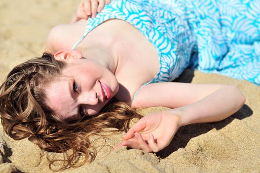 pretty longhaired  girl laying on the sand in sunny day