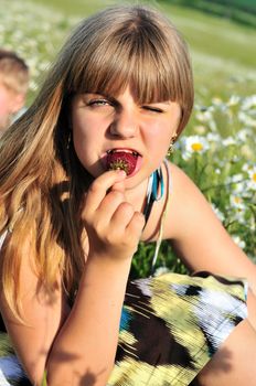teen funny girl eating fresh strawberry outdoors