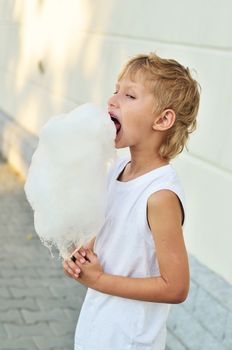 funny boy eating and enjoying cotton candy outdoors