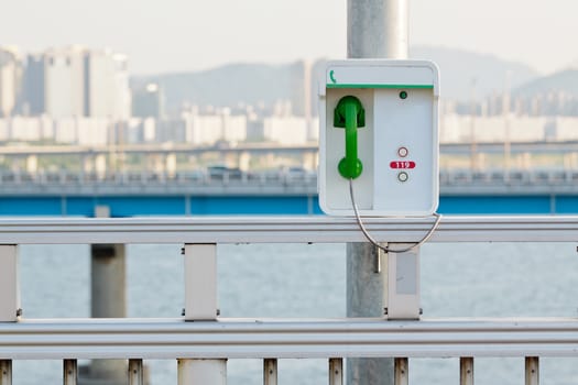 Emergency phone with a green handset on a bridge in Seoul
