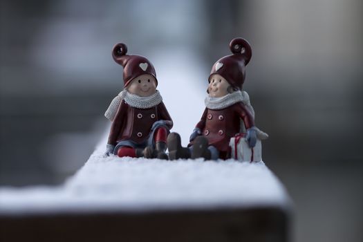 Two small christmas figures on a frosty Rail