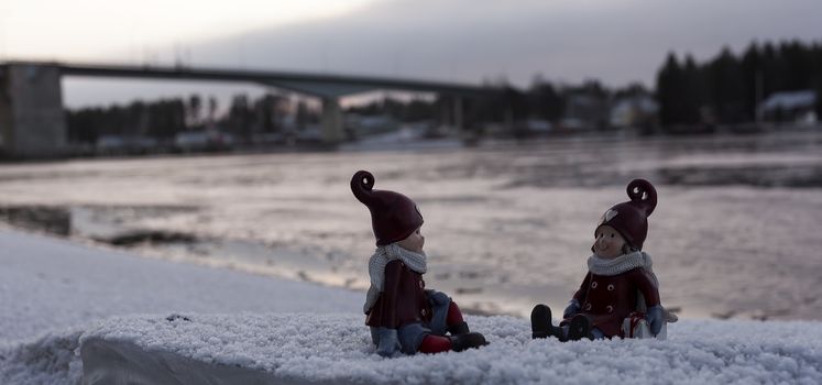 Two figures on an ice block infront of a bridge in the winter