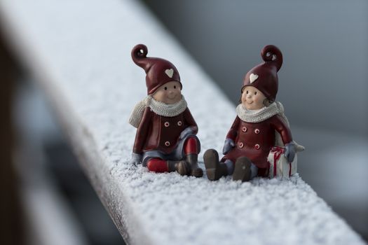 Two small christmas figures on a rail