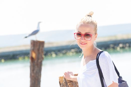 Portrait of a stylish lady strolling on the beach. Summertime feeling.