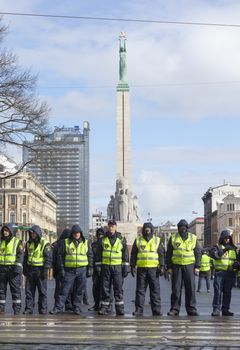 RIGA, LATVIA - MARCH 16, 2014: Police line infront Freedom Monument ready to prevent provocations at Commemoration of Latvian Legion (Waffen SS) unit. Event is drawing crowds of nationalists & antifascist demonstrators.