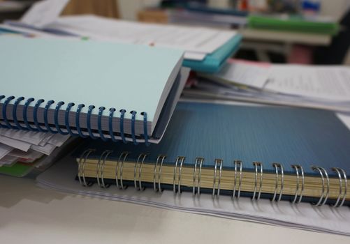 Notebook with a spiral spine and document placed on the desk in the office.                               