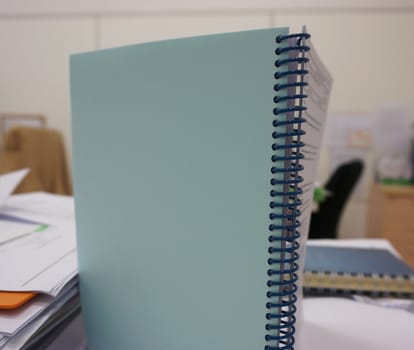 Notebook with spiral spine placed vertically on  desk in office.                               