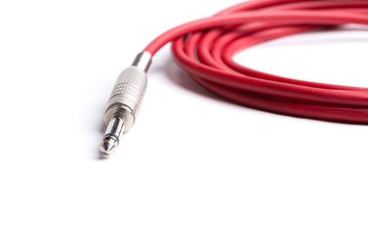 A red quarter inch cable for electric guitar isolated on a white background.