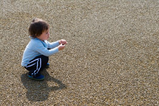 A 2 year old boy playing with a rock.
