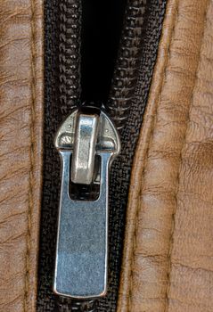 A macro shot of a zipper on a brown leather jacket.