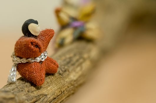 A macro shot of a very small hand made Japanese Doll sitting on a small branch.