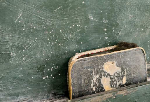 An old falling apart eraser on a green chalkboard.