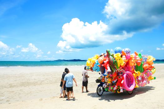 RAYONG,THAILAND-MAY 07,2015 :The man ride mobile shop selling toys to child on the beach in Eastern of Thailand.