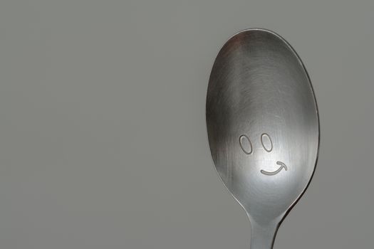 A silver spoon with a smiley face.
