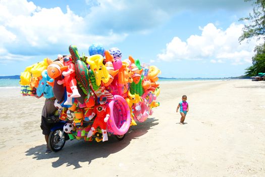 RAYONG,THAILAND-MAY 07,2015 :The man ride mobile shop selling toys to child on the beach in Eastern of Thailand.