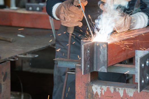 A welder welding creating sparks and smoke.