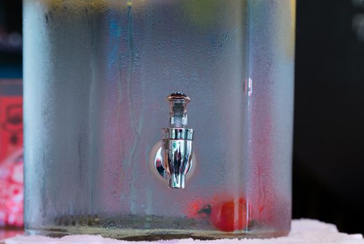 A pitcher of cold water with a tomato in it with condensation on the outside.