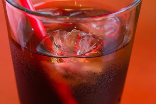 A glass of cold cola with ice and condensation on the outside.