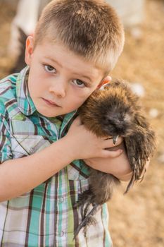 Caucasian boy outside carrying his pet chicken