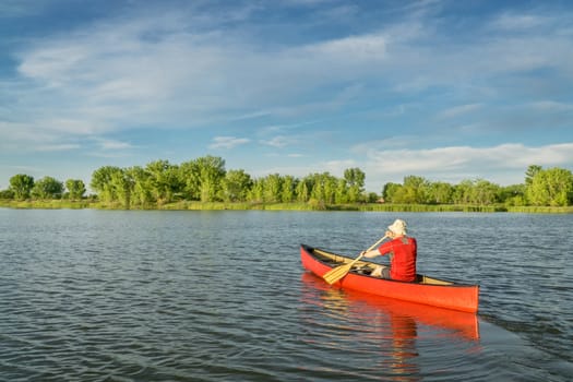 male paddler paddling a red canoe on a local lake in Fort Collins, Colorado