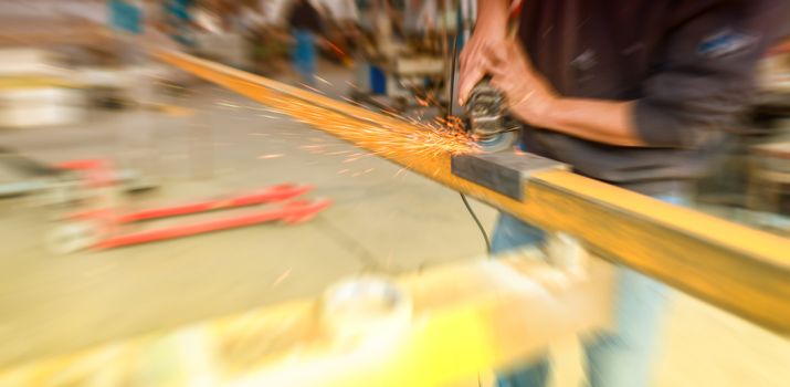 Electric wheel grinding on steel structure in factory.