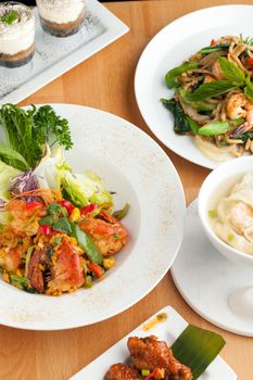 Varieties of Thai foods and appetizers covering a table. Shallow depth of field.